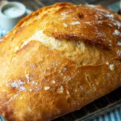 Ein frisch gebackenes Brot mit knuspriger Kruste liegt auf einem Holzbrett. Der Duft von **schwaden backen** liegt in der Luft.