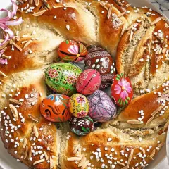 Ein festlicher Osterkranz aus Hefeteig, verziert mit bunten Ostereiern, Mandeln und Zuckerperlen.