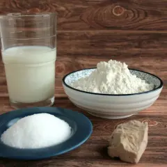 Milch, Mehl, Zucker und ein Stück Hefe liegen bereit. Die Grundzutaten für einen perfekten Hefeteig.