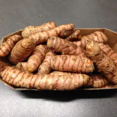 Frische Kurkuma-Wurzeln in einer Pappschale, bereit für leckere Kurkuma-Wurzel-Rezepte.