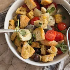 Herzhafter Brotsalat mit Roggenbrot, Kirschtomaten, Oliven und Artischockenherzen, garniert mit frischen Kräutern.