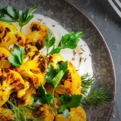 Gerösteter Blumenkohl mit Kurkuma, garniert mit frischer Petersilie und Dill, serviert mit einer cremigen Sauce. Perfekt als Beilage oder Hauptgericht.