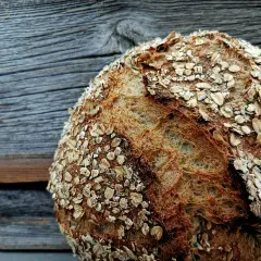 Ein rustikales, reines Haferbrot mit knuspriger Kruste, bestreut mit Haferflocken. Perfekt für ein gesundes Frühstück.