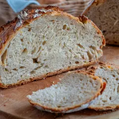 Ein frisch gebackenes Buttermilch Brot mit knuspriger Kruste und luftiger Krume, auf einem Holzbrett angeschnitten.