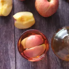 Ein Glas mit Apfelschnitzen und eine Flasche Apfelessig stehen bereit. Zeit, Apfelessig zu trinken!