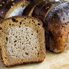 Frisches Brot, aufgeschnitten auf einem Holzbrett. Die Frage, ob man Brot zweimal einfrieren kann, beschäftigt viele.