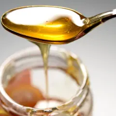 Ein Löffel mit goldenem Honig tropft in ein Glas. Hoffentlich kein schlechter Honig gegessen!