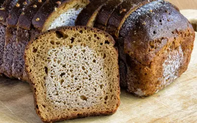 Frisches Brot, aufgeschnitten auf einem Holzbrett. Die Frage, ob man Brot zweimal einfrieren kann, beschäftigt viele.