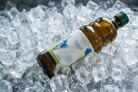 Flasche mit leinöl direkt von der mühle, gekühlt in Eiswürfeln.
