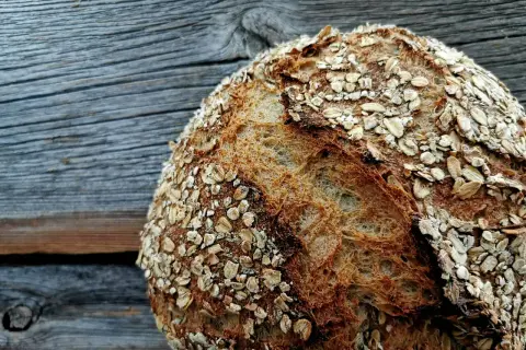 Ein rustikales, reines Haferbrot mit knuspriger Kruste, bestreut mit Haferflocken. Perfekt für ein gesundes Frühstück.