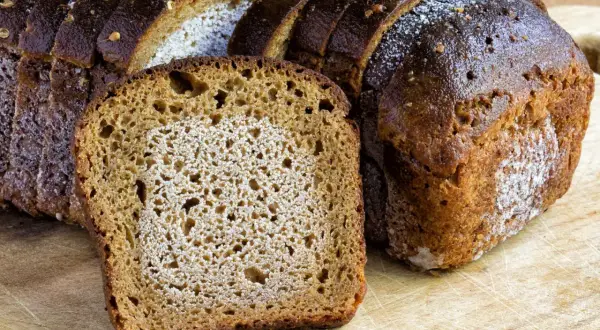 Frisches Brot, aufgeschnitten auf einem Holzbrett. Die Frage, ob man Brot zweimal einfrieren kann, beschäftigt viele.