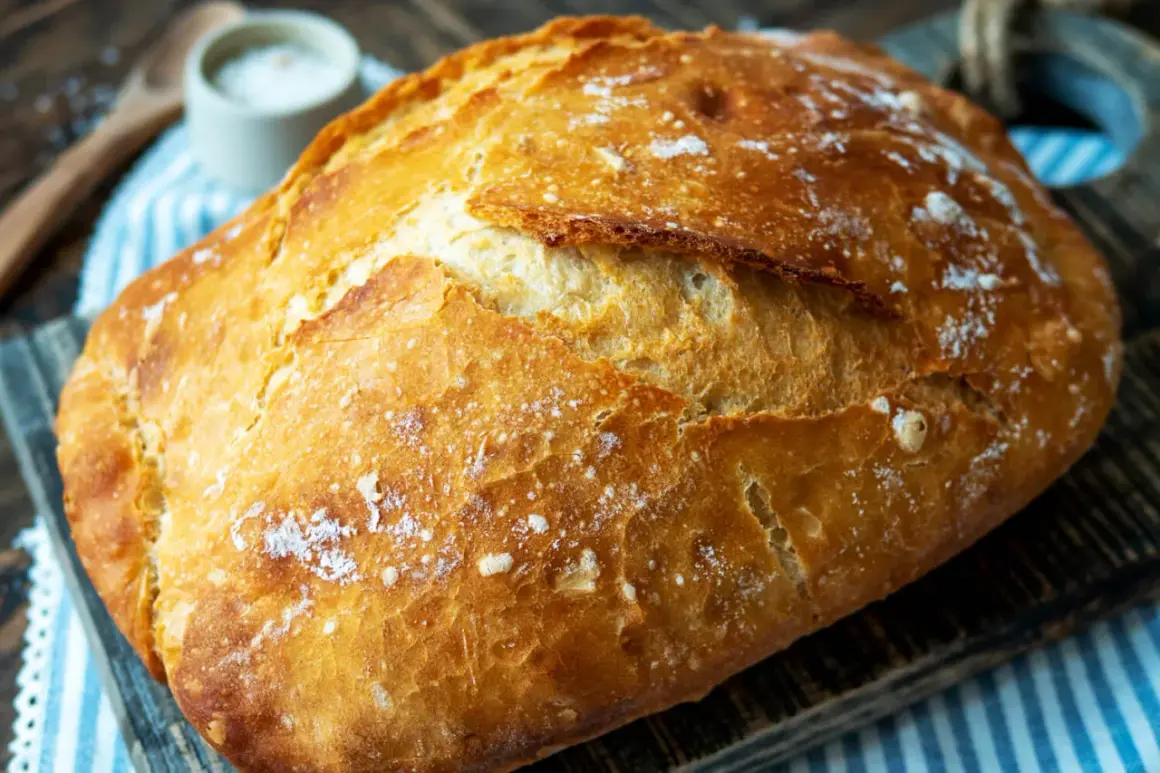 Ein frisch gebackenes Brot mit knuspriger Kruste liegt auf einem Holzbrett. Der Duft von **schwaden backen** liegt in der Luft.
