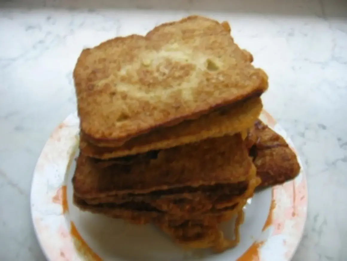 Ein Stapel goldbraunes Brot mit Ei, auf einem Teller angerichtet. Perfekt für ein herzhaftes Frühstück.