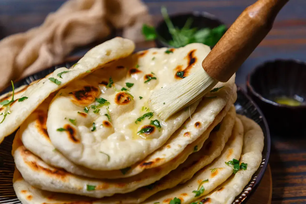 Frisch gebackenes Naan Brot, mit Butter bestrichen und mit Kräutern garniert, bereit zum Servieren aus der Pfanne.
