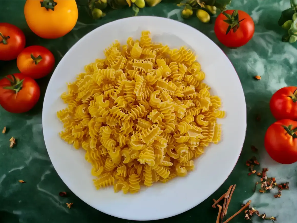Ein Teller mit gedrehten Nudeln, die aus Hartweizengrieß hergestellt sind, umgeben von frischen Tomaten und Gewürzen.