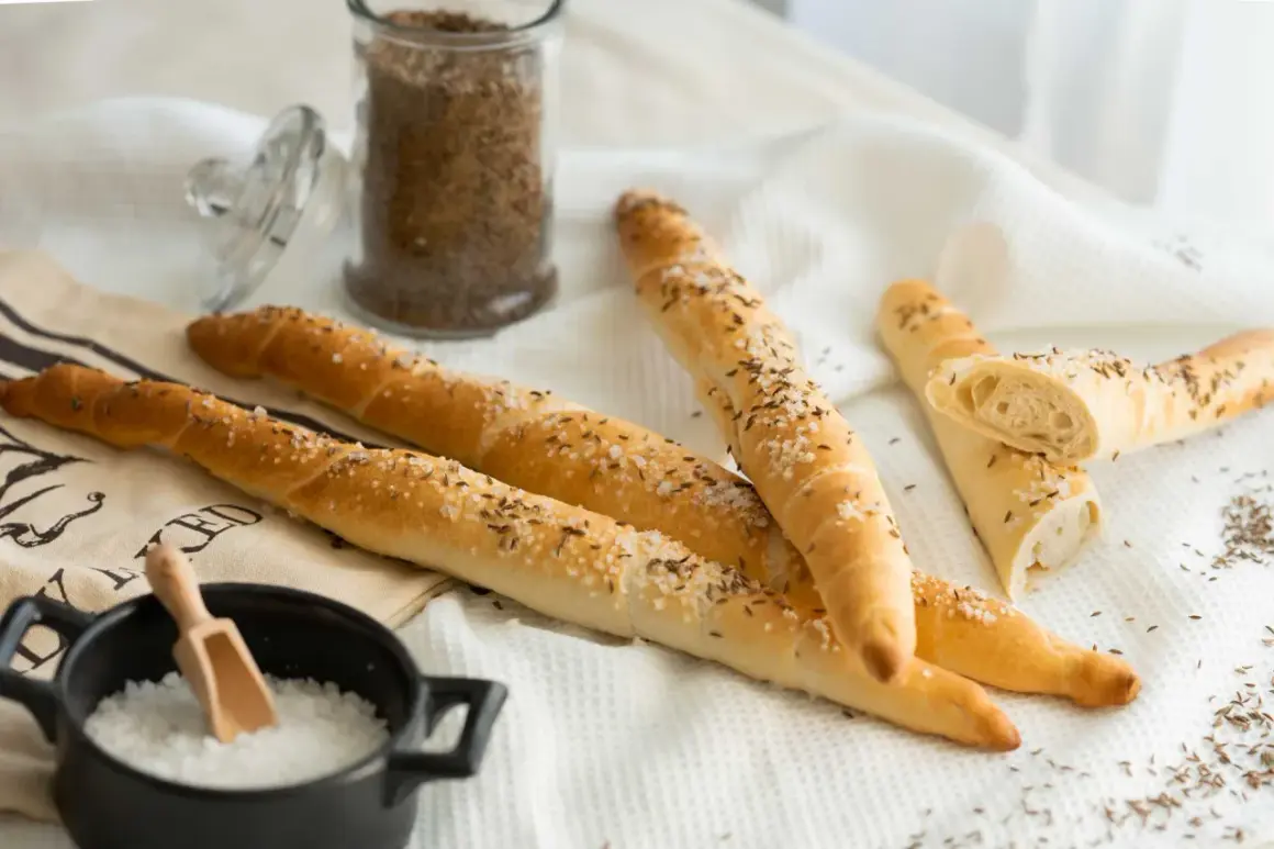 Goldbraune Salzstangen mit Kümmel und grobem Salz, bereit zum Genießen. So einfach kannst du Salzstangen selber machen!