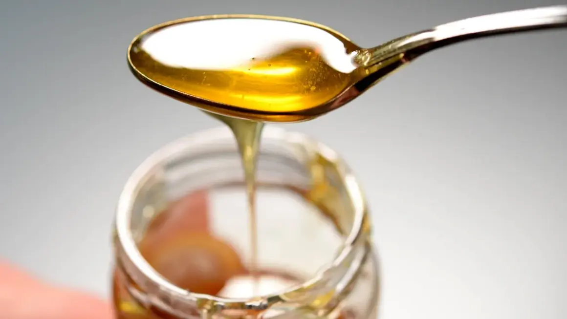 Ein Löffel mit goldenem Honig tropft in ein Glas. Hoffentlich kein schlechter Honig gegessen!