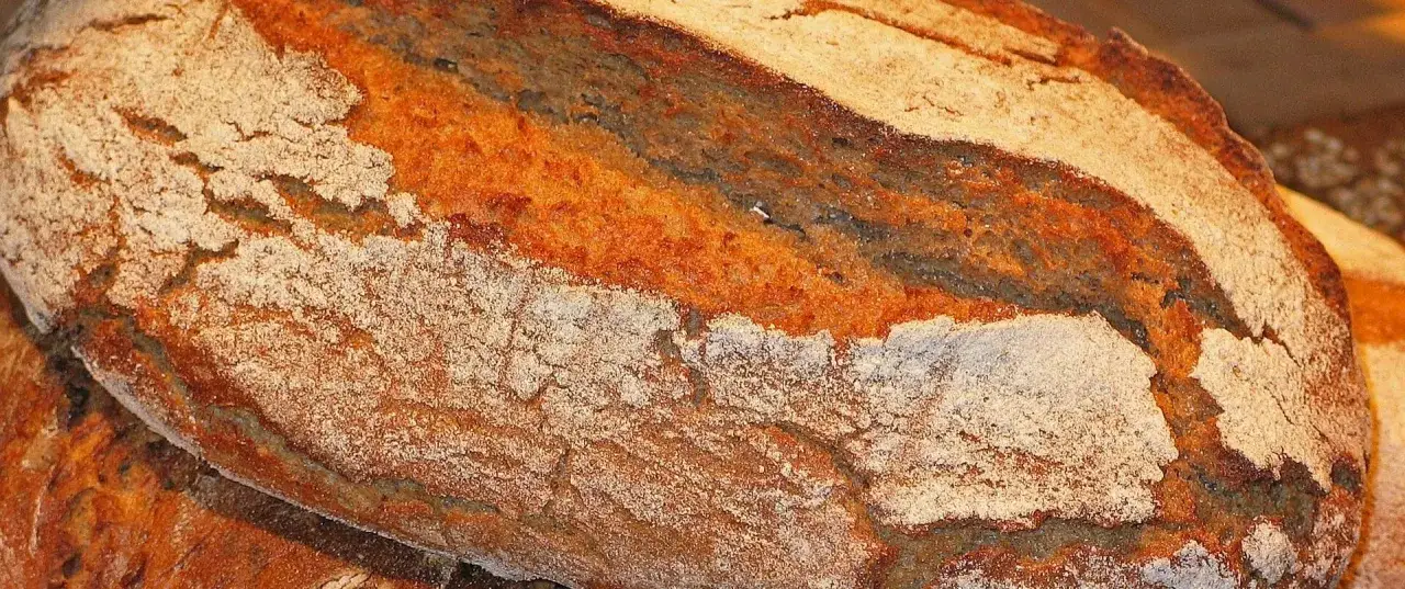 Nahaufnahme eines rustikalen Brotes mit knuspriger Kruste und sichtbarer brot krume. Die Textur ist grob und einladend.