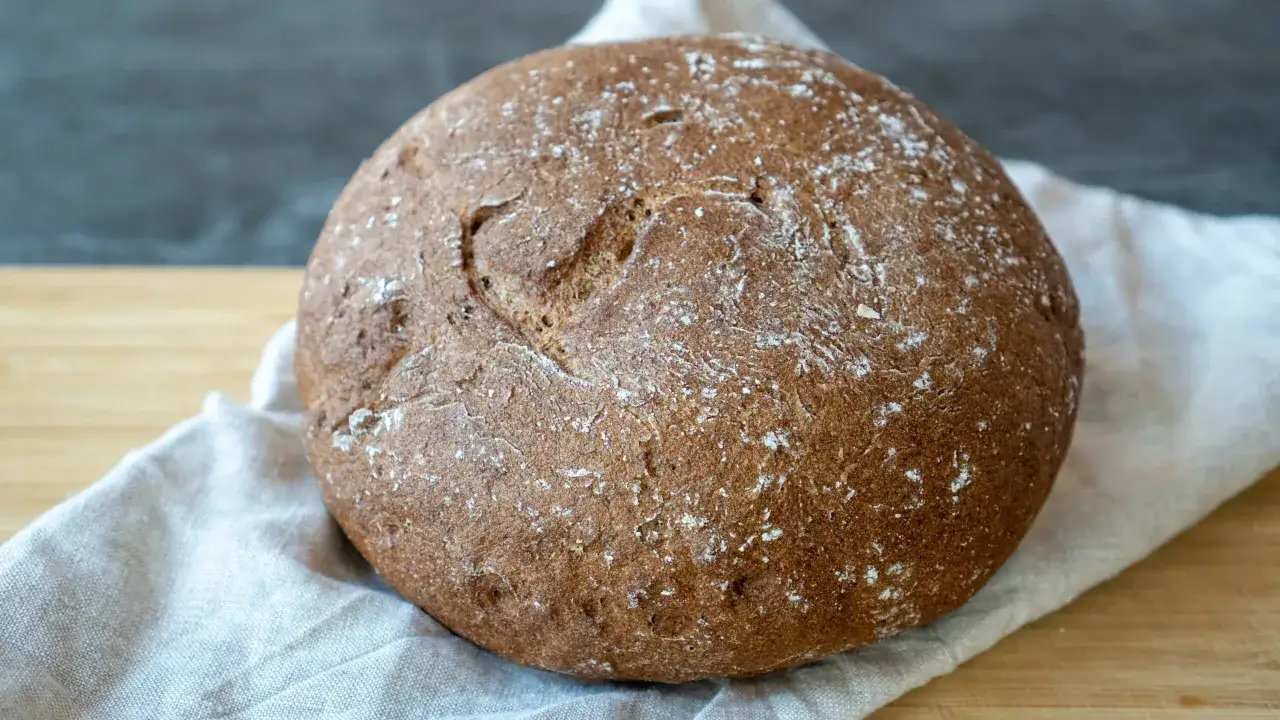Ein rustikales Brot mit einer Herzform im Teig, gebacken aus glutenhaltigem Mehl.
