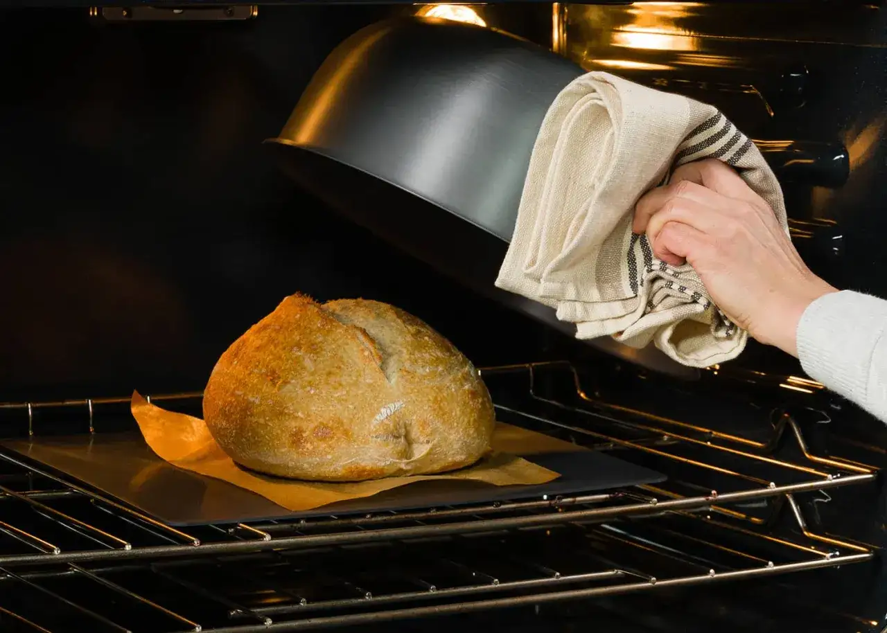 Ein Laib Brot wird im Ofen mit einem Deckel bedeckt, um die Kruste weich zu halten. Das Backen von Brot ist eine Kunst.