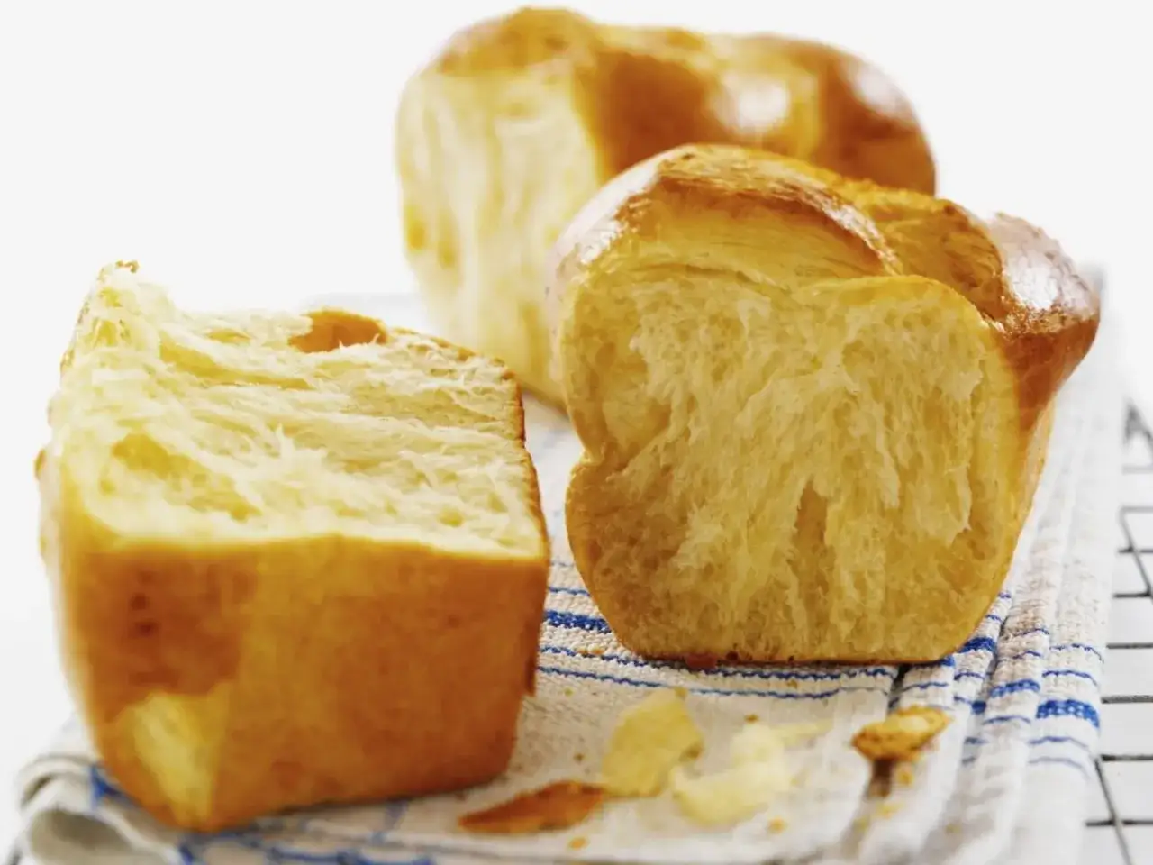 Frisch gebackener Hefeteig mit Milch, goldbraun und fluffig. Ein St&uuml;ck ist angeschnitten und zeigt die zarte Krume.