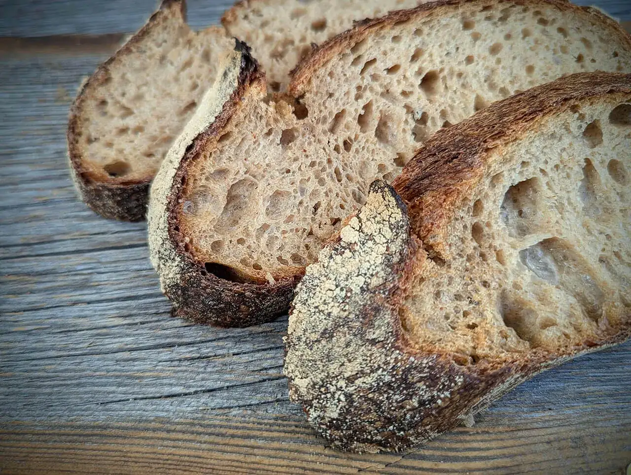 Schnittflächen von rustikalem Ruchbrot mit knuspriger Kruste auf Holz. Ein tolles Ruchbrot Rezept!
