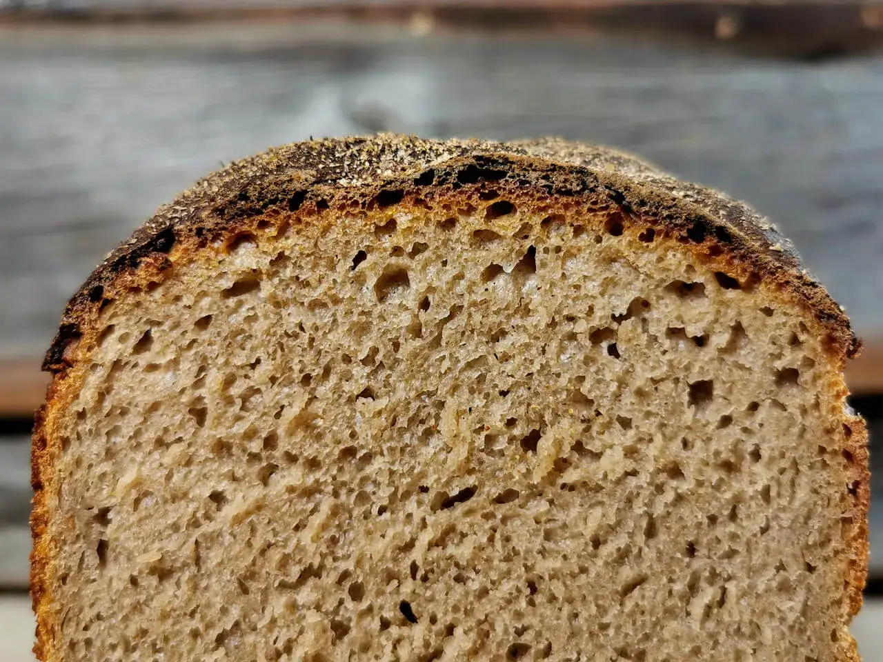 Nahaufnahme einer aufgeschnittenen Brotscheibe mit luftiger, goldbrauner brot krume und knuspriger Kruste.