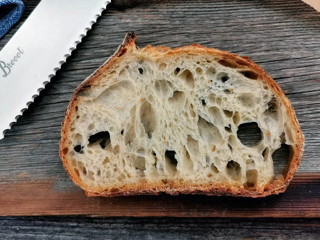 Schnitt eines Sauerteigbrotes mit großer Porung, das Ergebnis von guter Sauerteig Hefe. Daneben ein Brotmesser.