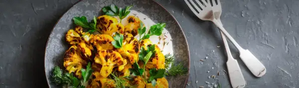 Gerösteter Blumenkohl mit Kurkuma, garniert mit frischer Petersilie und Dill, serviert mit einer cremigen Sauce. Perfekt als Beilage oder Hauptgericht.